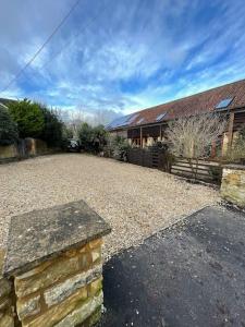 a house with a gravel driveway in front of a house at Escape to a Cosy Country Barn: Discover the Charm of Rustic Living 