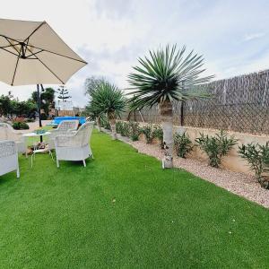 a garden with a table and chairs and an umbrella at La Gardana, casa de campo mallorquina in Porreres