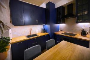 a kitchen with dark blue cabinets and a wooden table at apartament Legnicka 33 Wrocław in Wrocław