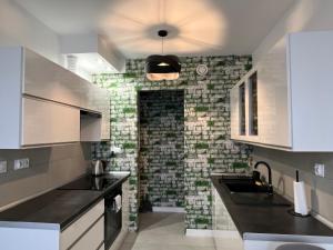 uma cozinha com uma parede de tijolos e um lavatório em Apartament Nikodema em Leszno