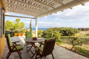 a table and chairs on a patio with a view of the ocean at Bralos Villa - Paros, Sea View in Kóstos