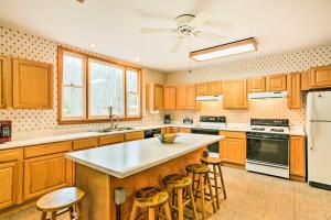 una cocina con armarios de madera y una isla de cocina con taburetes en Cozy Wilcox Home on East Branch of Clarion River! en Wilcox