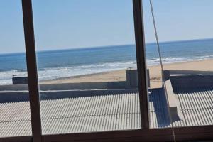 a view of a beach from a glass window at Swakopmund holiday Apartment in Swakopmund