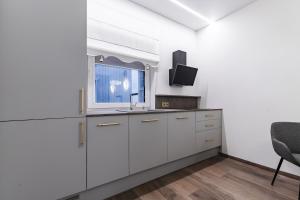 a white kitchen with a sink and a window at Amber Stone Apartment 1st floor in Palanga