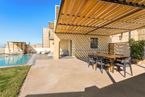 a patio with a table and chairs under a wooden pergola at Mani Theasis in Stoupa