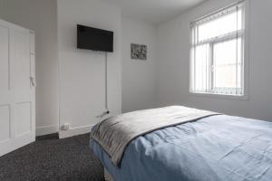 ein Schlafzimmer mit einem Bett und einem TV an der Wand in der Unterkunft Home in Levenshulme, Manchester in Manchester