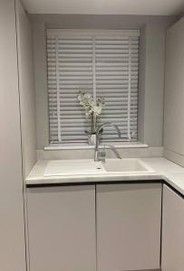 a kitchen sink with a vase of flowers in a window at Rivendell Modern 2 Bedroom apartment in St Peters village sleeps 6 in Kent