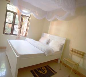een wit bed in een kamer met ramen bij Kakakuona Resort in Lushoto