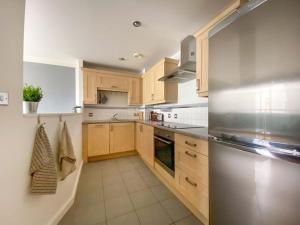 a kitchen with wooden cabinets and a stainless steel refrigerator at Beautifully Presented 2 Bedroom Apartment in Liverpool