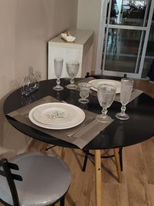 uma mesa preta com pratos e copos de vinho em LOFT ENCANTADOR COM PISCINA, VAGA, WiFi, TV 50" em São Paulo