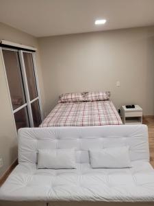 Sofá blanco en una habitación con cama en LOFT ENCANTADOR COM PISCINA, VAGA, WiFi, TV 50", en São Paulo