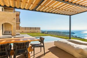 a patio with a table and chairs and a view of the ocean at Mani Theasis in Stoupa