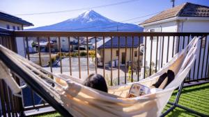 Eine Frau in einer Hängematte mit einem Berg im Hintergrund in der Unterkunft OriOri House Hotel Mt Fuji view 全室富士山ビューの貸切り宿 折々 in Fujikawaguchiko