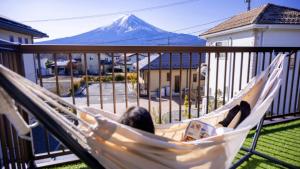 a woman laying in a hammock with a mountain in the background at OriOri House Hotel Mt Fuji view 全室富士山ビューの貸切り宿 折々 in Fujikawaguchiko