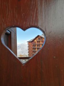 a heart shaped window with a view of a building at RISOUL 1850 Appartement T2 confortable skis aux pieds à 300 m centre in Risoul