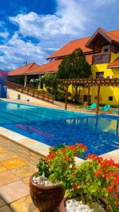 - une piscine avec deux plantes en pot à côté d'une maison dans l'établissement Pousada Granville, à Campina Grande