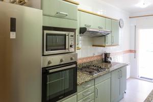 a kitchen with green cabinets and a microwave at CASA CON JARDIN-WIFI FREE in L'Escala