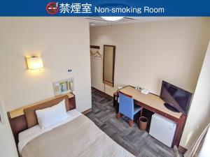 een kamer met een bed en een bureau met een monitor bij Kadoma Public Hotel in Kadoma