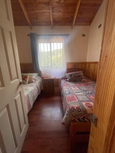Habitación pequeña con 2 camas y ventana en Cabaña en Licanray, en Villarrica
