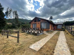 una cabaña de madera con una valla y una casa en Cabaña en Licanray, en Villarrica