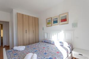ein Schlafzimmer mit einem Bett und einem Schrank mit Gemälden an der Wand in der Unterkunft APARTAMENTO PIE DE PLAYA-Wifi free in L'Escala