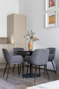 a table with four chairs and a vase on it at Amber Stone Apartment 2nd floor in Palanga