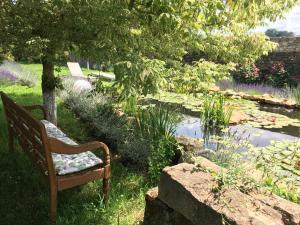 a bench sitting in the grass next to a pond at Domaine de la Mance - Maisonnette avec cheminée, bain nordique en supplément in Vitrey