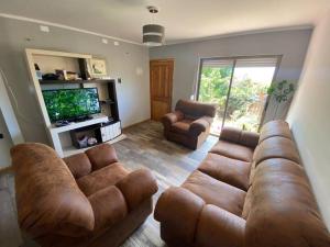 a living room with a brown couch and a television at Casa amoblada, Los Vilos in Los Vilos