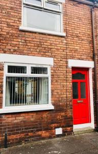 a brick building with a red door and a window at Cosy House, Lisburn Road in Belfast