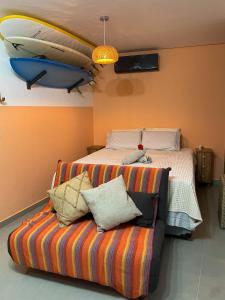 1 dormitorio con 1 cama y 1 sofá con tabla de surf en la pared en Flat alto padrão próximo ao mar de Maracaípe, en Ipojuca