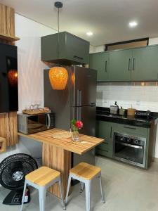 una cocina con armarios verdes y una mesa con 2 sillas en Flat alto padrão próximo ao mar de Maracaípe, en Ipojuca
