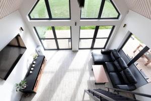 a living room with black leather furniture and large windows at Tartu Pajuoja saunamaja in Tartu