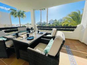 d'un balcon avec une table, des chaises et des palmiers. dans l'établissement Blue Palm Apartment Estepona, à Estepona