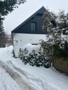 dom ze śniegiem na ziemi obok płotu w obiekcie Apartamenty Slowianka w mieście Wolibórz
