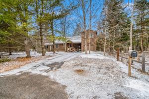 a home in the woods with a snow covered driveway at The River Retreat in Thompsonville
