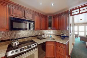 a kitchen with wooden cabinets and a sink and a microwave at Skyland Studio in Crested Butte