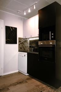 una cocina con electrodomésticos negros y armarios blancos en Stylish house in the heart of Lapland in Tornio, en Tornio
