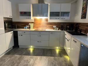 cocina con armarios blancos y pared de madera en Ferienwohnung am Bodensee- zentrale Lage, free parking and wifi, 109 m2, privater Garten, 7 Gäste, 2x Kingsize Boxspringbett, familienfreundlich, en Friedrichshafen