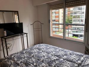 1 dormitorio con 1 cama, TV y ventana en Arce en Buenos Aires