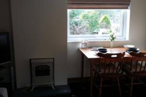 Tudor Cottage, Newby Bridge في أولفيرستون: غرفة طعام مع طاولة ونافذة