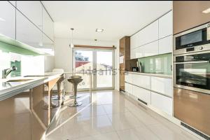uma cozinha com armários brancos e electrodomésticos de aço inoxidável em Riverside - apartment em Cruz Quebrada