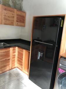 eine Küche mit einem schwarzen Kühlschrank und Holzschränken in der Unterkunft Condominio Pacha en Tulum in Tulum