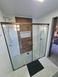 a bathroom with a shower with glass doors at Aconchego Ipê Amarelo in Gramado