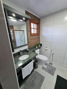 a bathroom with a sink and a toilet and a mirror at Aconchego Ipê Amarelo in Gramado