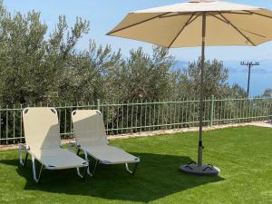 two chairs and an umbrella on the lawn at Appartement Villa Pasithea in Xiropigado