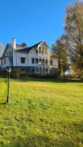 una grande casa bianca con un prato erboso di Skogsbrynet B&B, Bredsjö Nya Herrgård a Hällefors