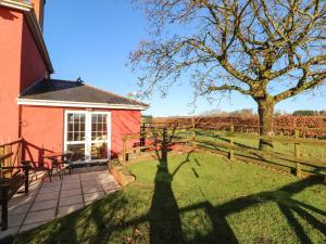 einen Hof mit einem roten Haus und einem Baum in der Unterkunft Cwtch Cowin in Banc-y-felin