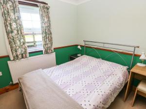 um pequeno quarto com uma cama e uma janela em Cwtch Cowin em Banc-y-felin