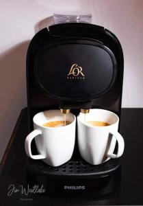 two cups of coffee being brewed in a coffee machine at Olive Tree self-catering accommodation in Olvera