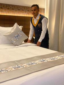 a man is standing next to a bed at فندق اسين in Al Madinah